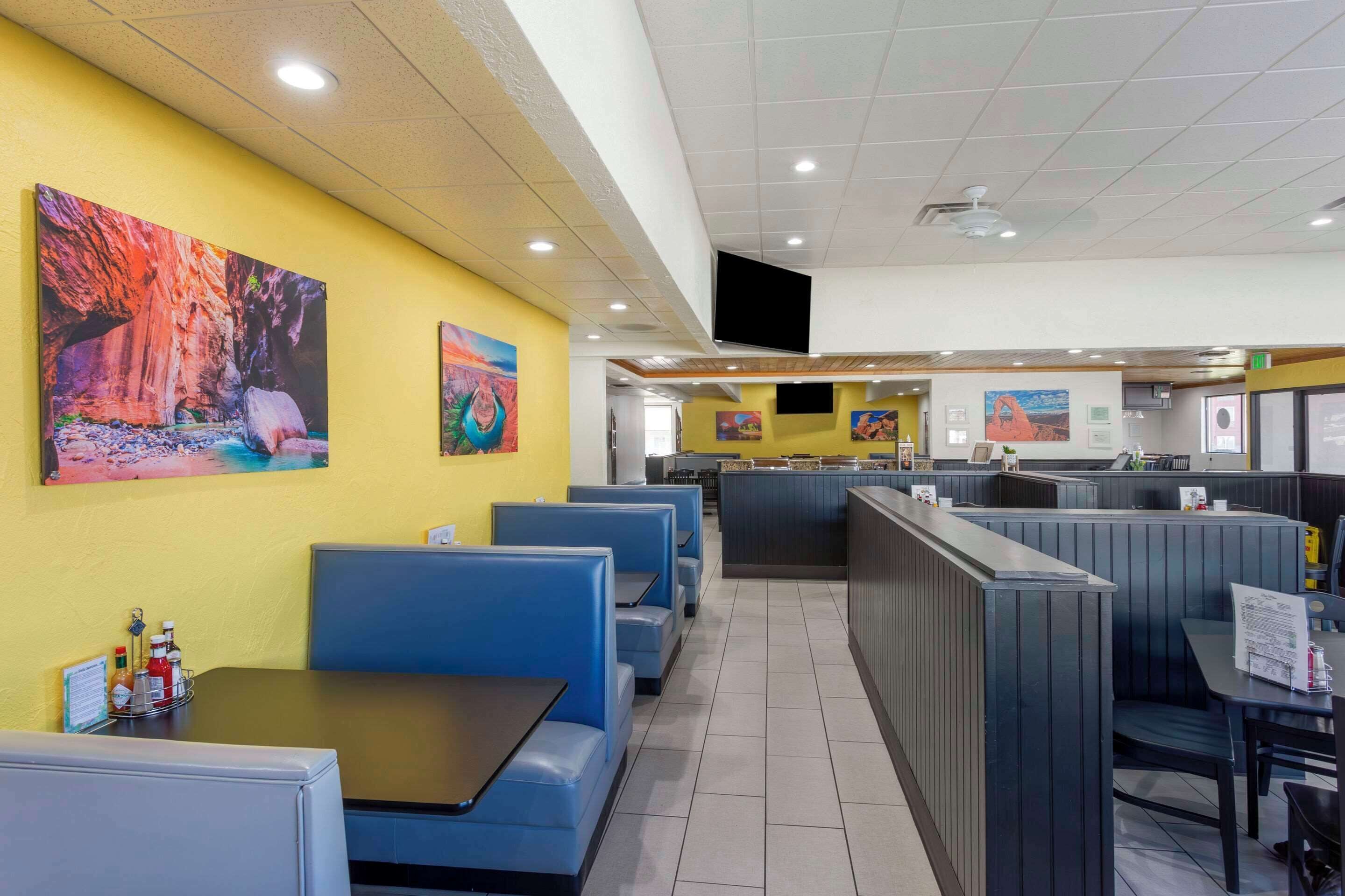 A restaurant with booths and tables, yellow walls, and artwork on the walls.