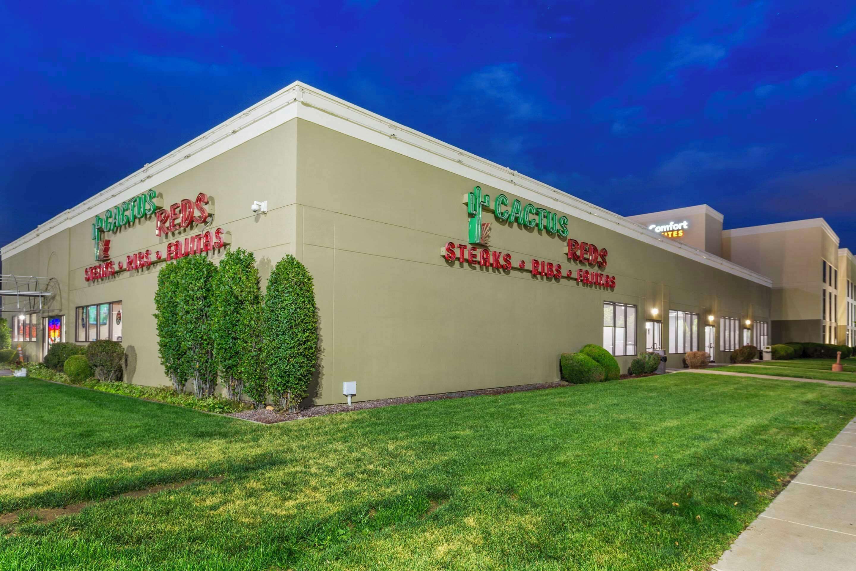 A building with signage for 'Cactus Reds' featuring steaks, ribs, and fruits.