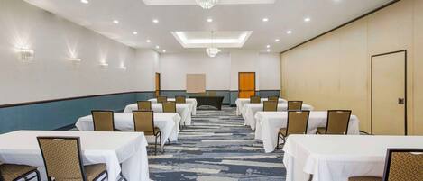A conference room with tables and chairs, a patterned carpet, and a chandelier.