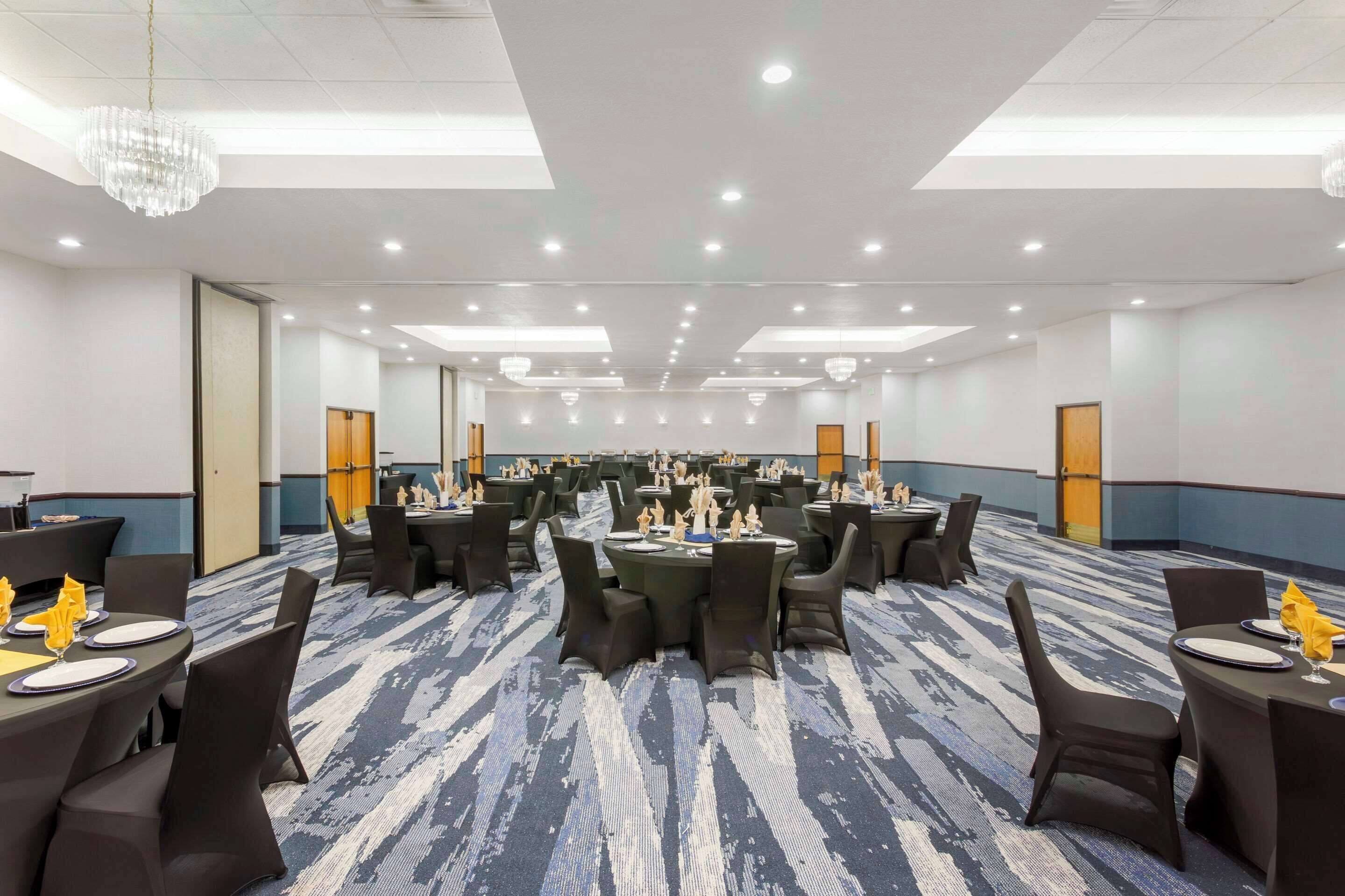 A large conference room with round tables and chairs, equipped with nameplates and napkins.