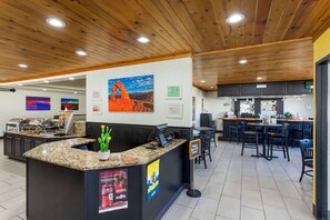 A reception area with a counter, seating, and a kitchen in the background.
