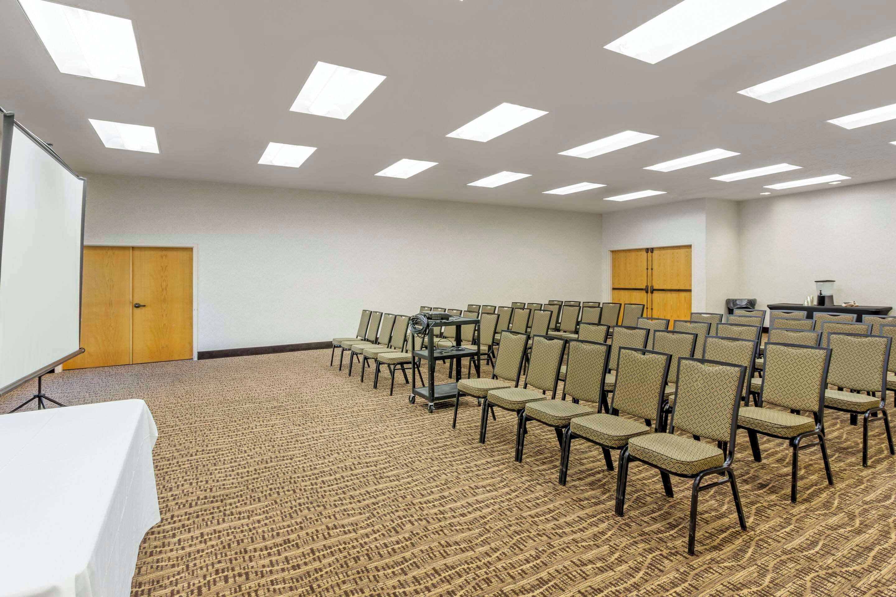 A conference room with rows of chairs, a projector screen, and a podium.