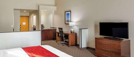 A hotel room with a bed, a desk, a chair, a television, and a dresser.