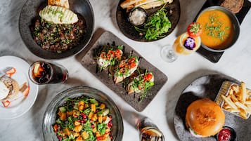 A variety of dishes including a burger, fries, a salad, and a bowl of soup.