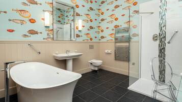 Une salle de bain équipée d’une baignoire, d’un lavabo, de toilettes et d’une douche à parois en verre.