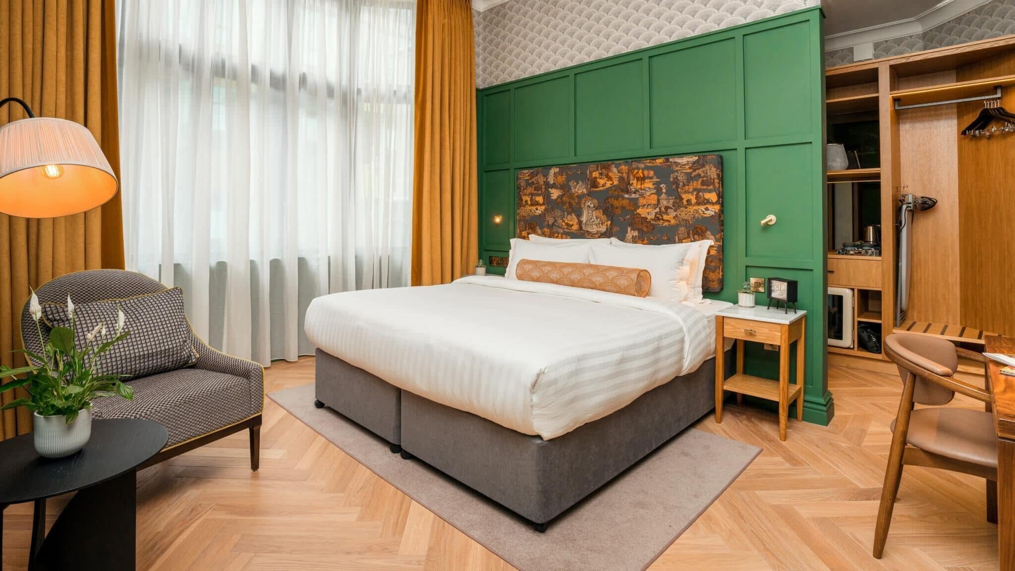 Une chambre d’hôtel bien aménagée, avec un grand lit, un bureau et une chaise.