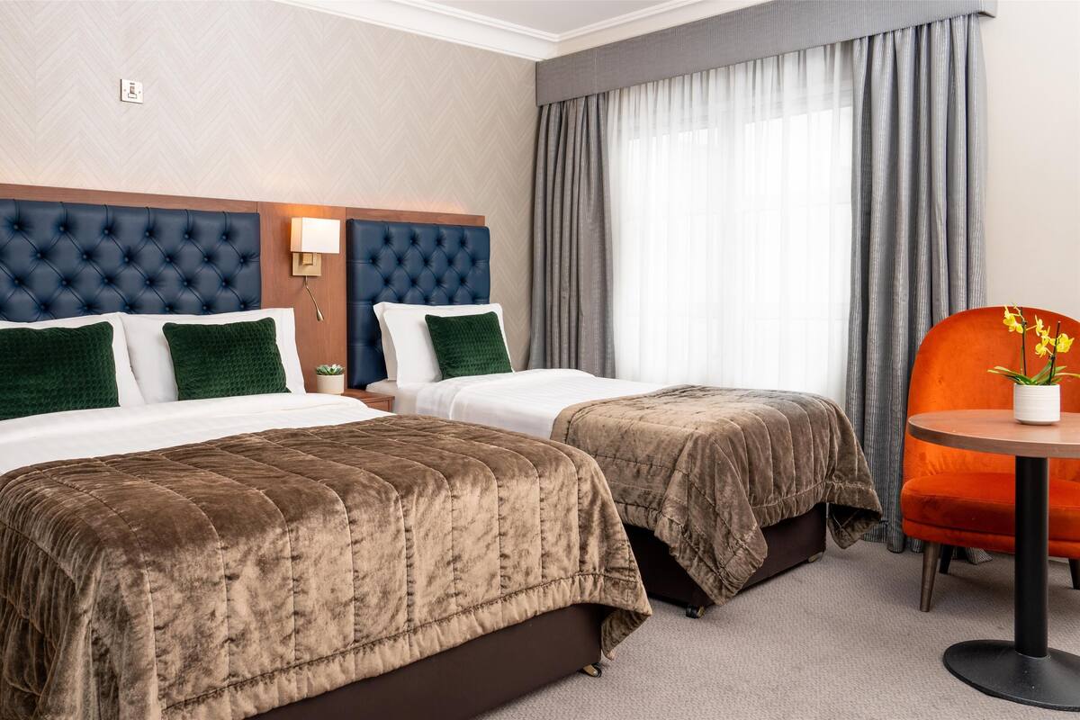 Habitación de hotel con dos camas, una mesita y una silla.