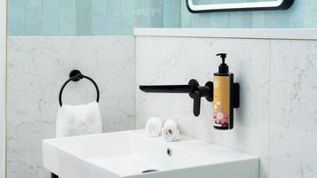 Un baño con lavamanos blanco, grifo negro y espejo con marco negro.