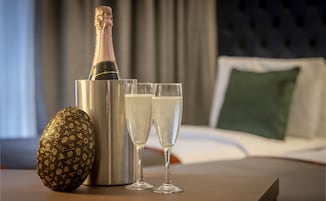 Una botella de champán, dos copas y un adorno sobre una mesa en una habitación de hotel.