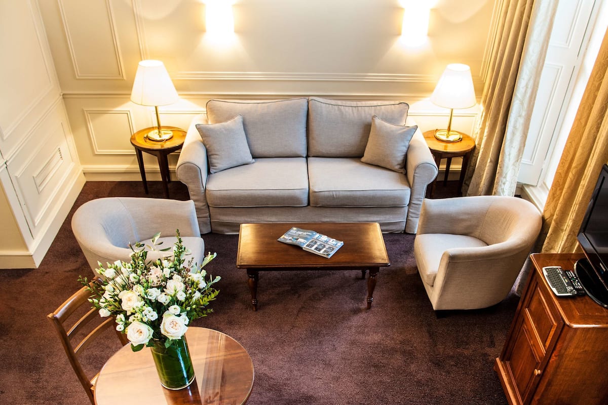 Un salon comprenant un canapé, deux fauteuils, une table basse et une table d’appoint avec une lampe.