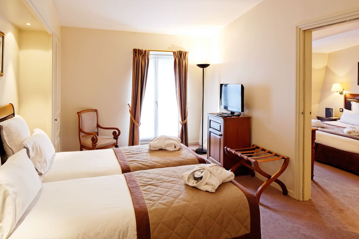 Une chambre d’hôtel avec deux lits, une télévision, un bureau et une chaise.