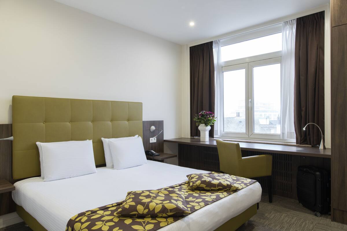 Habitación de hotel con una cama grande, un escritorio y una ventana con cortinas.