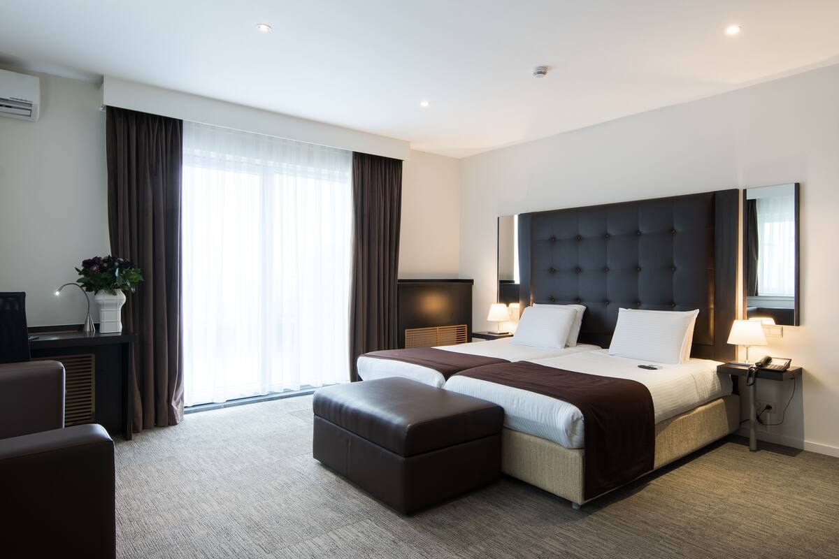 Una habitación de hotel moderna con una cama grande, un escritorio, una silla y una ventana con cortinas.