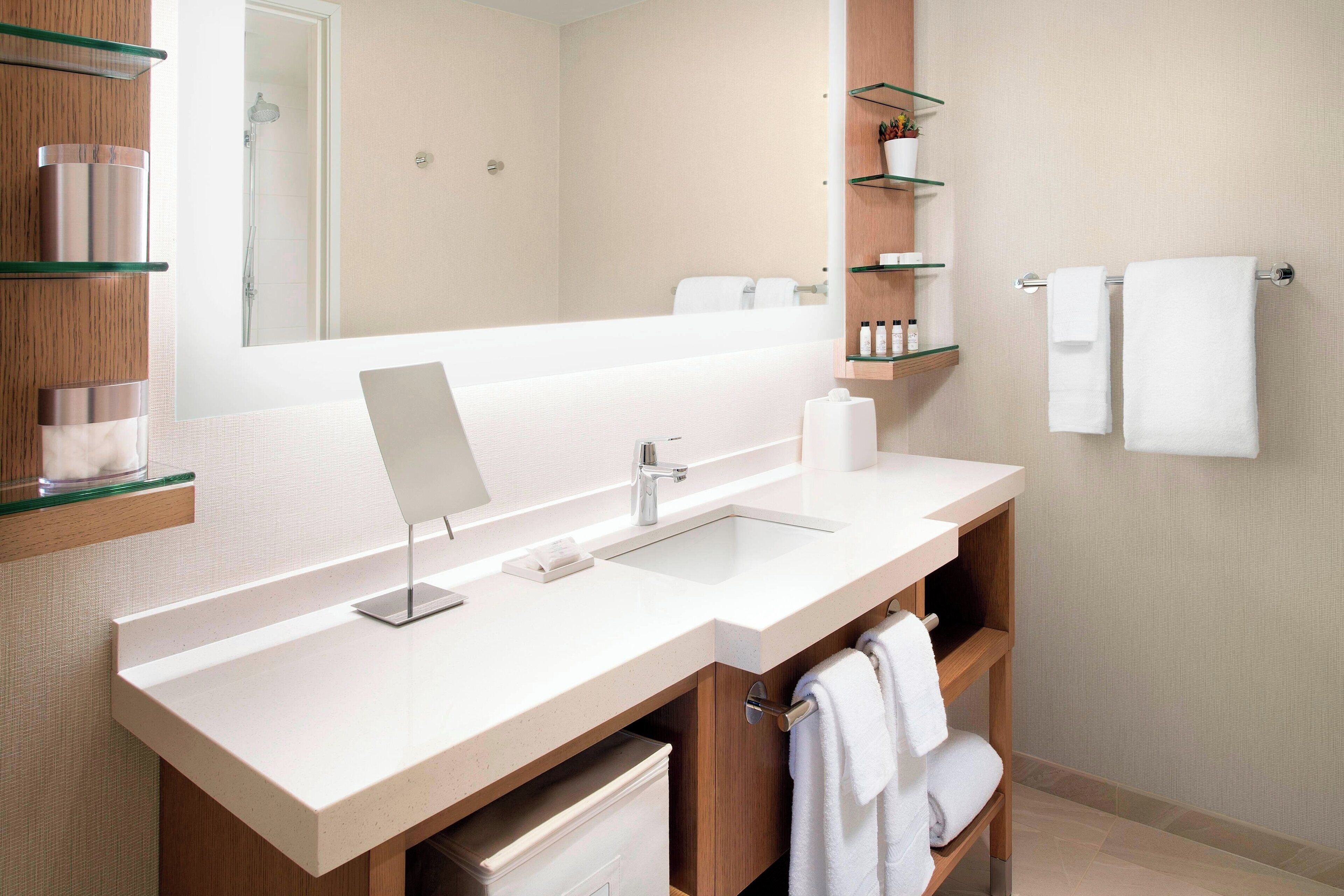 A modern bathroom with a large mirror, two sinks, and wooden cabinets.