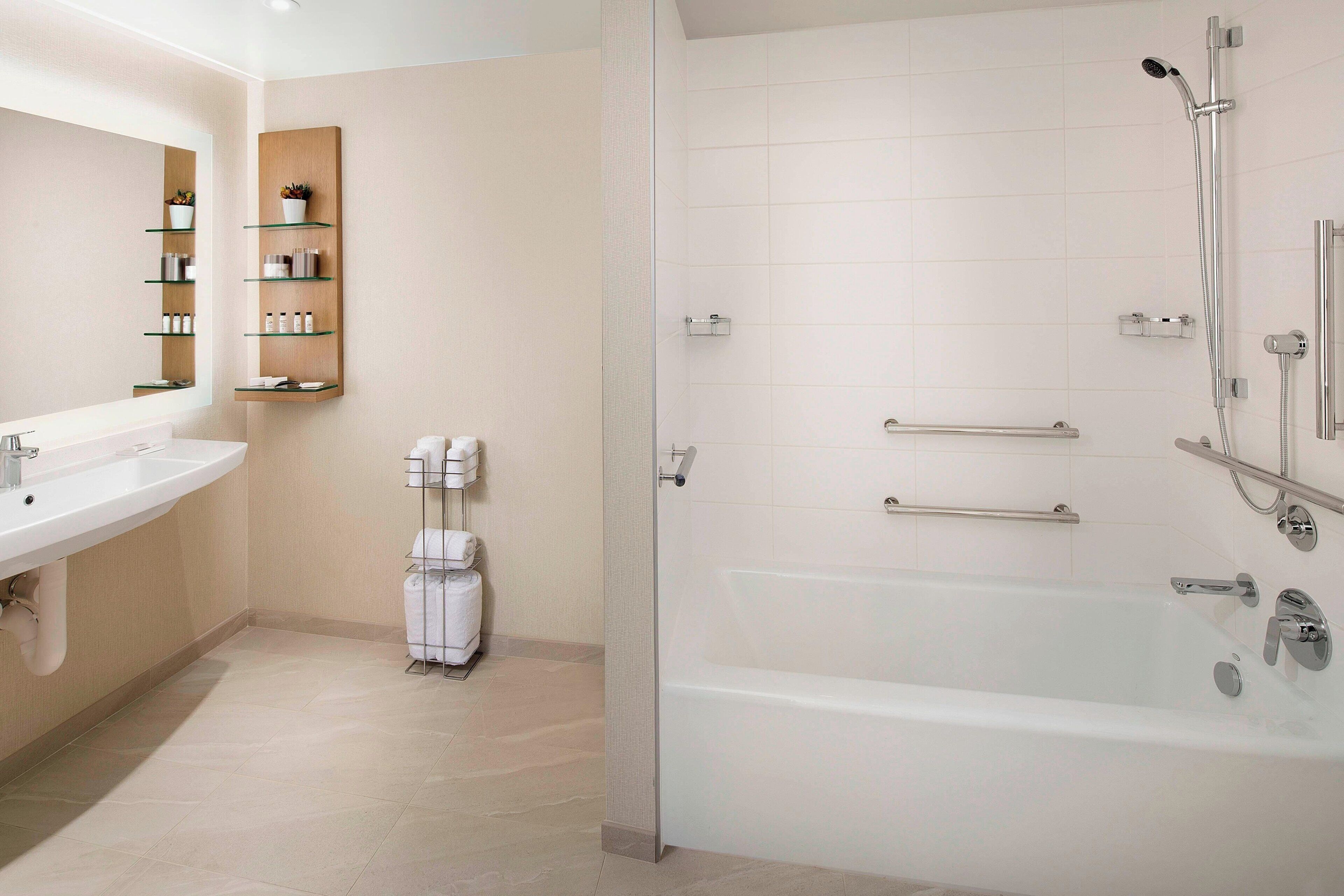 Un bany modern amb dutxa tancada per vidre, un lavabo blanc i una prestatgeria integrada amb productes de tocador.