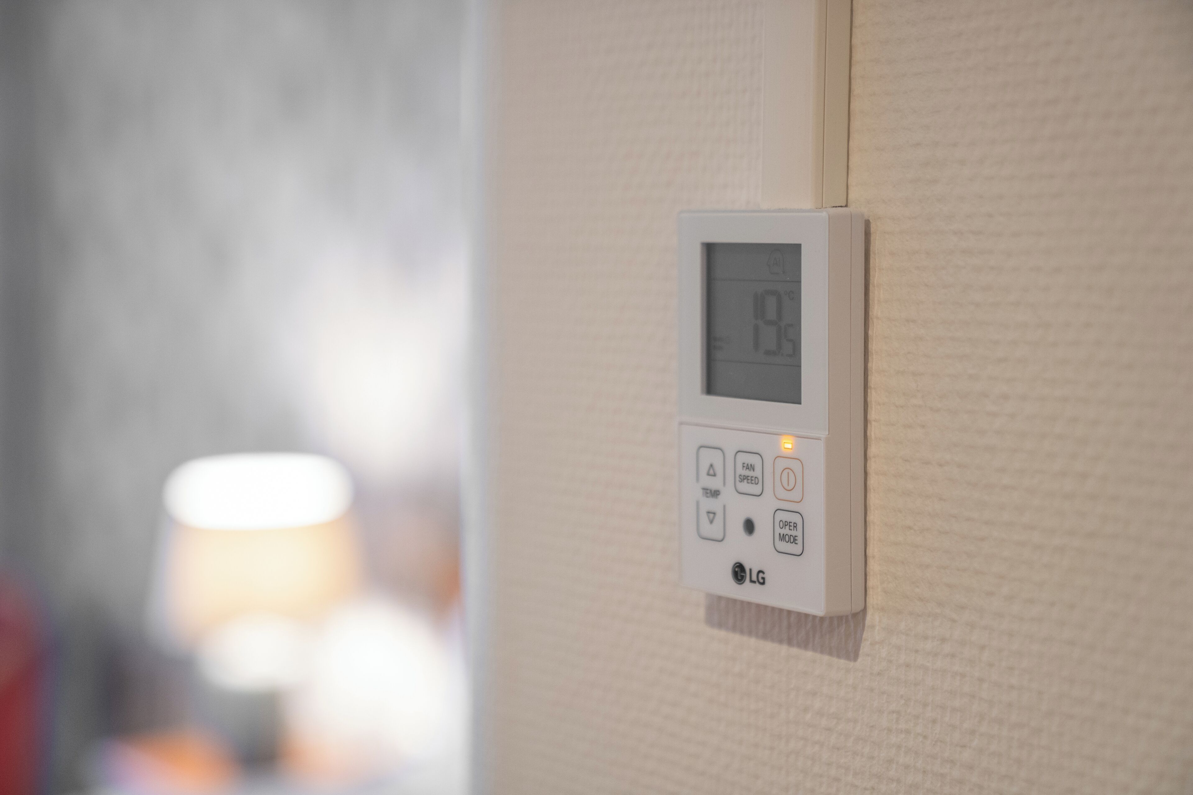 Een thermostaat bevestigd aan een structuurwand, toont een temperatuur van 19°C.