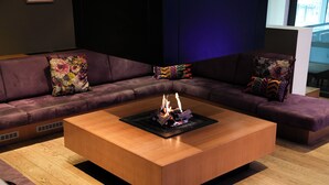 Una sala de estar moderna con una mesa de centro de madera, un sofá modular morado y almohadones de colores.