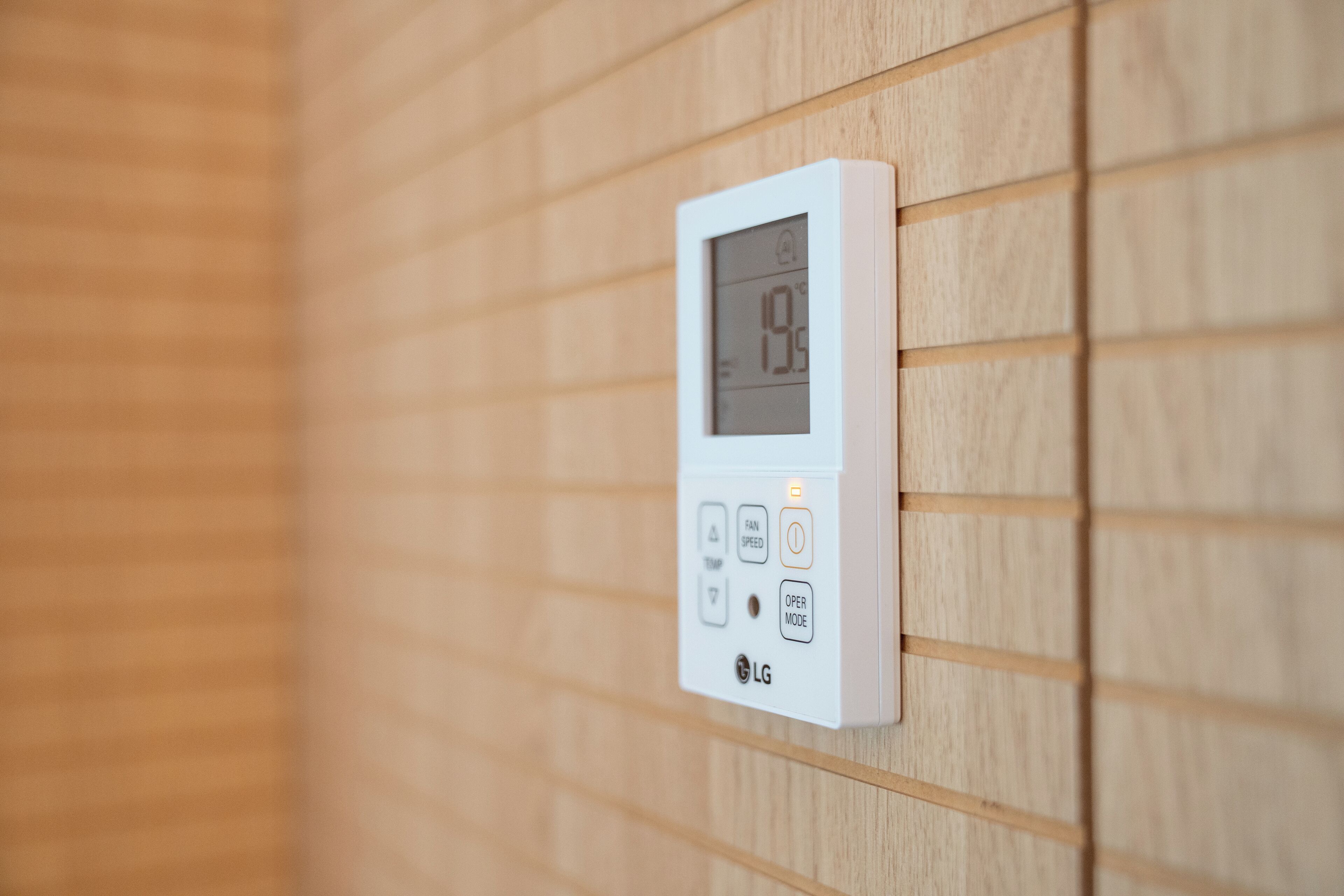 Un termostato fijado a la pared, con pantalla digital, botones de control y el logotipo de LG.