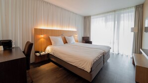 Una habitación de hotel moderna con una cama grande, un escritorio y una silla.