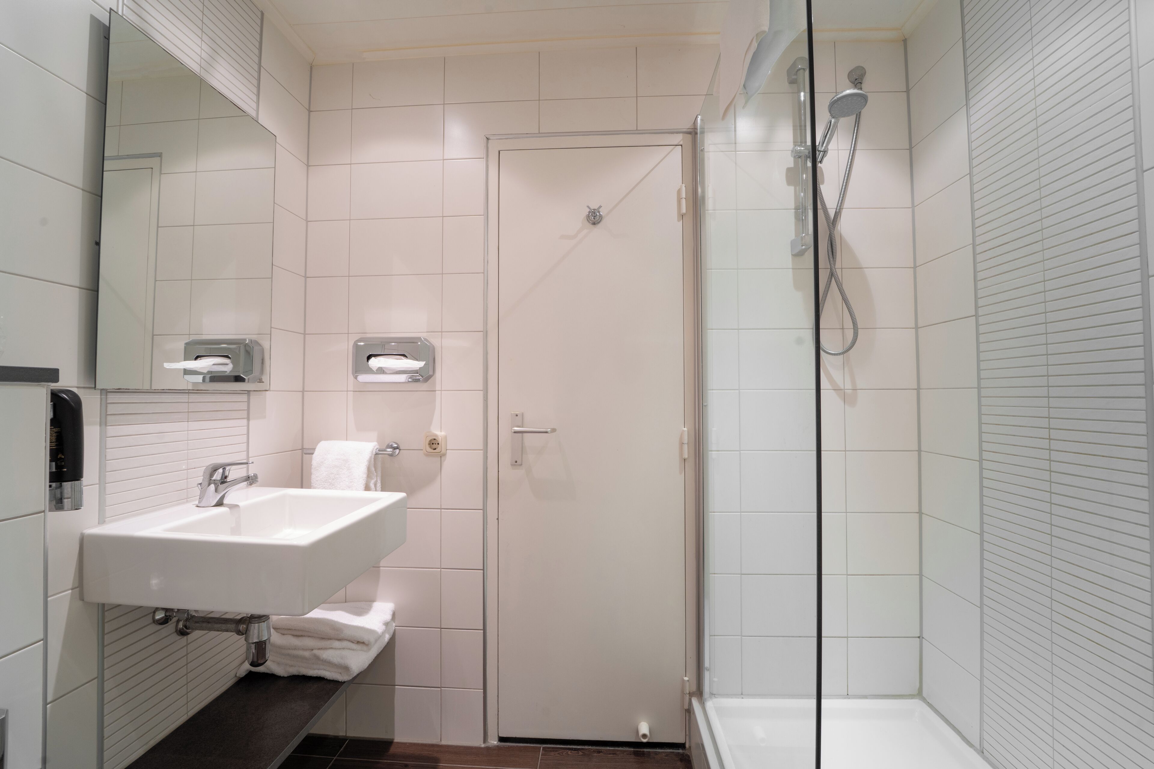 A modern bathroom with a white sink, mirror, and shower.
