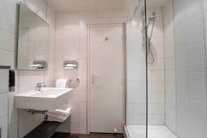 Ein modernes Badezimmer mit Waschbecken, Spiegel und Dusche in Weiß.