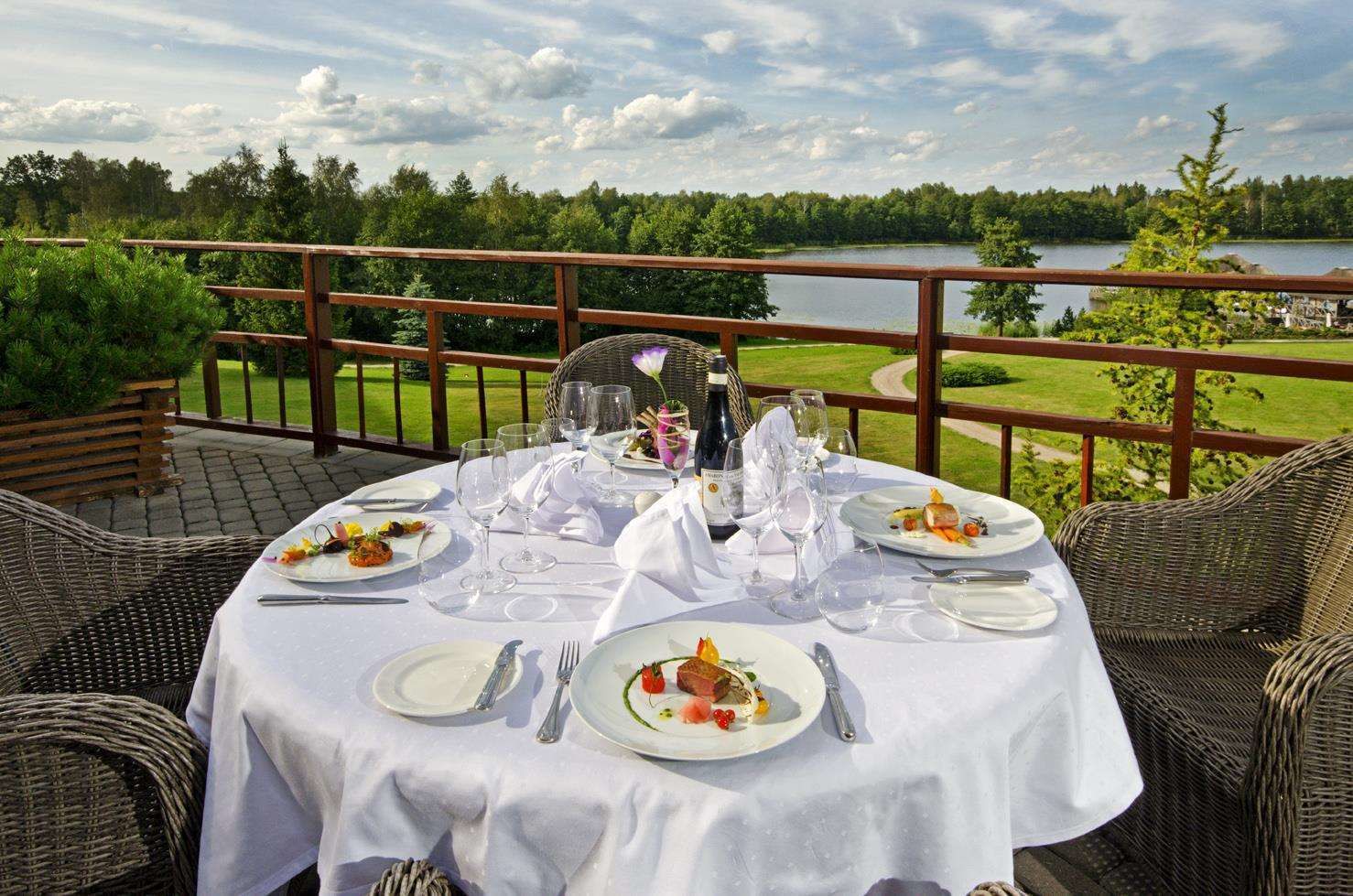 A table set for a meal with a view of a lake and forest.