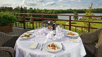 A table set for a meal with a view of a lake and forest.