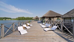 A wooden pier with lounge chairs and thatched-roof structures overlooking a lake. - Vilnius Grand Resort (Kalikstiškes)