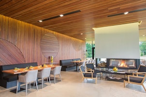 Un comedor moderno con una larga mesa de madera, sillas acolchadas y una chimenea.