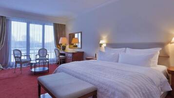 Habitación de hotel con una cama grande, un escritorio con dos sillas, una ventana con cortinas y vistas a la ciudad.