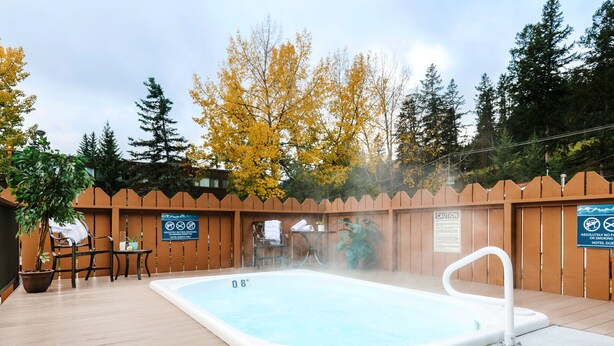 A hot tub with a wooden deck, surrounded by a wooden fence, and signs indicating smoking is not allowed. - Lobstick Lodge (Jasper)