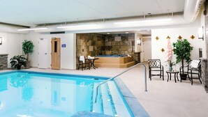 An indoor swimming pool with a stone wall, seating area, and a hot tub. - Lobstick Lodge (Jasper)