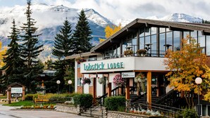 A lodge with a mountain backdrop, a signboard, and a staircase leading to the entrance. - Lobstick Lodge (Jasper)