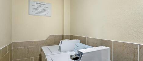 Área de lavandería para huéspedes, con aviso indicando uso exclusivo para clientes y eximiendo a la propiedad de responsabilidad por artículos perdidos o dañados.