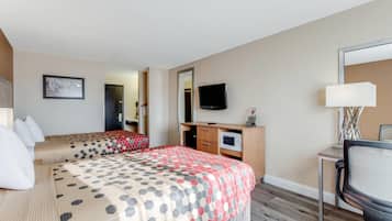 A hotel room with two beds, a desk with a chair, a television, and a microwave.