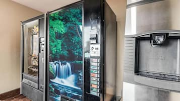 A vending machine with a waterfall image and a refrigerator with a hand symbol.
