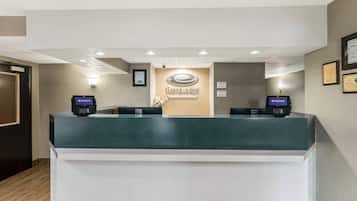 Bancada de recepção verde, dois terminais de pagamento e uma placa na parede com a inscrição 'EconomoLodge'.