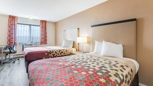 Habitación de hotel con dos camas, un escritorio y una silla.
