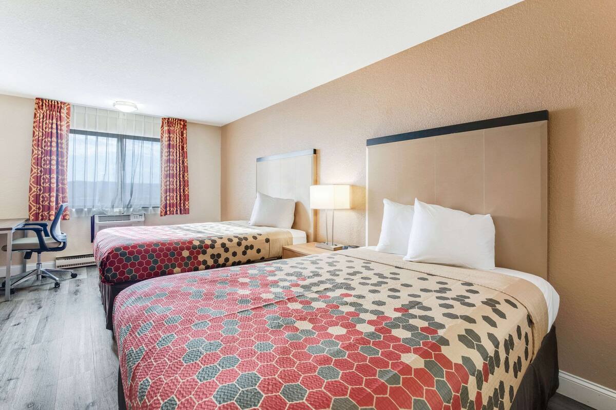 Ein Hotelzimmer mit zwei Betten, einem Schreibtisch und einem Stuhl.