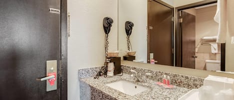 A bathroom with a sink, mirror, and hairdryer mounted on the wall.