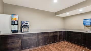 A modern kitchen with dark wood cabinets, a coffee machine, and a juice dispenser.