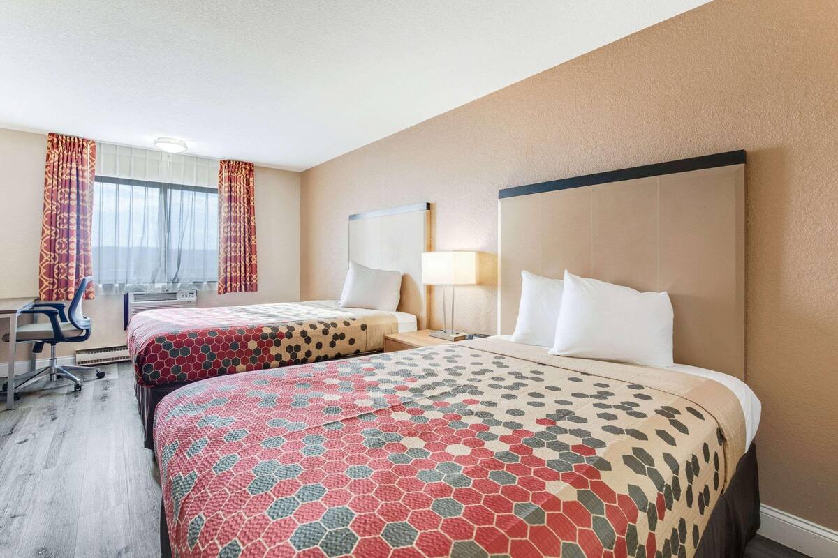 Ein Hotelzimmer mit zwei Betten, einem Schreibtisch und einem Sessel.