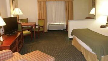A hotel room with a bed, a desk with a television, a chair, and a small couch.