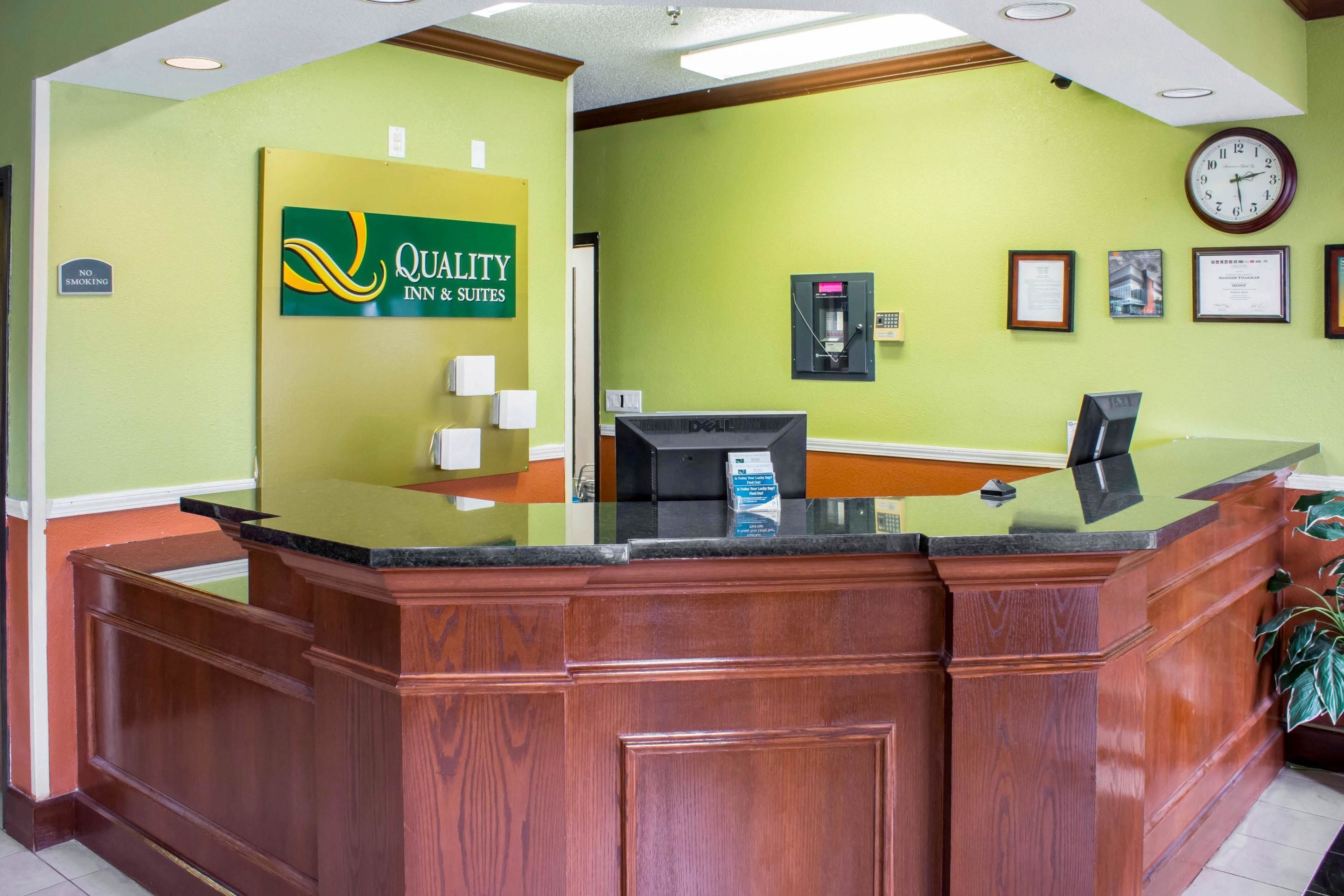 A reception desk with a green wall, a clock, framed certificates, and a "No Smoking" sign.