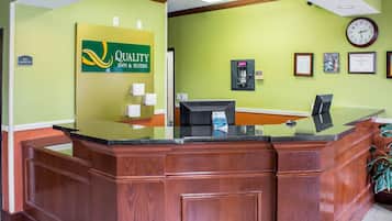 A reception desk with a green wall, a clock, framed certificates, and a "No Smoking" sign.