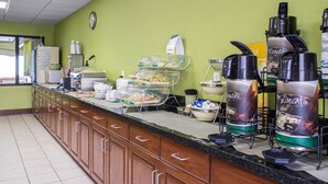 Una barra de desayuno con distintos alimentos y dispensadores de bebidas.