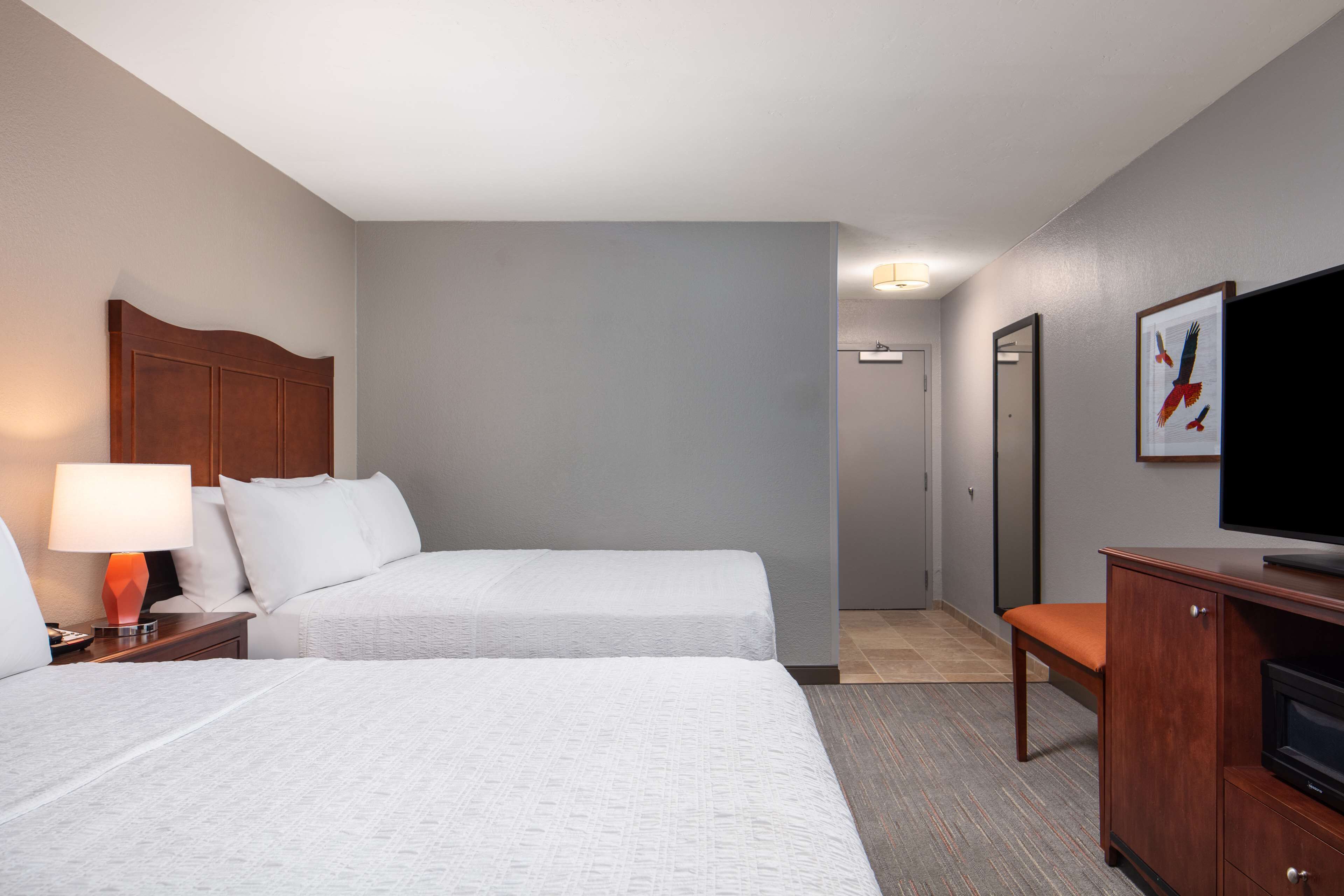 Quarto de hotel com duas camas, televisão, escrivaninha e uma cadeira.