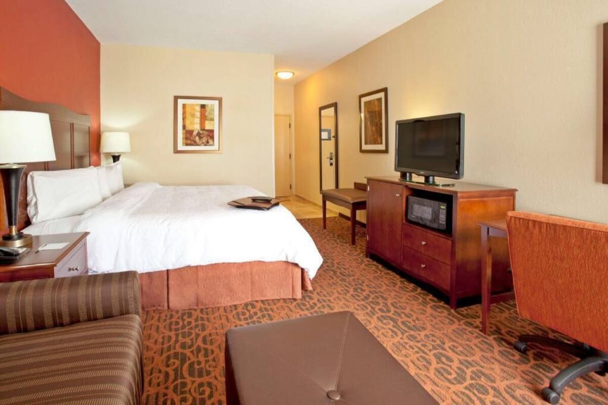 A hotel room with a bed, a desk with a computer, a television, and a chair.