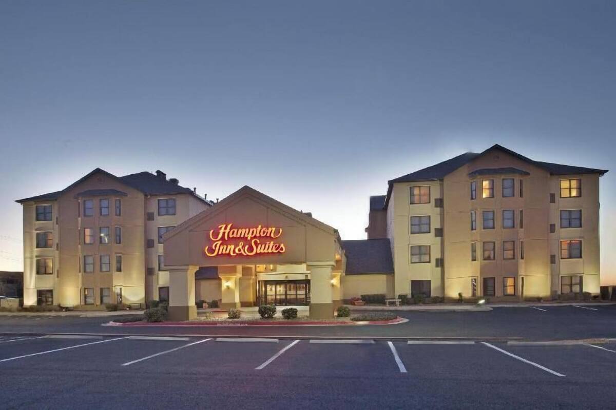 A Hampton Inn & Suites hotel with a large sign, multiple floors, and a parking lot.