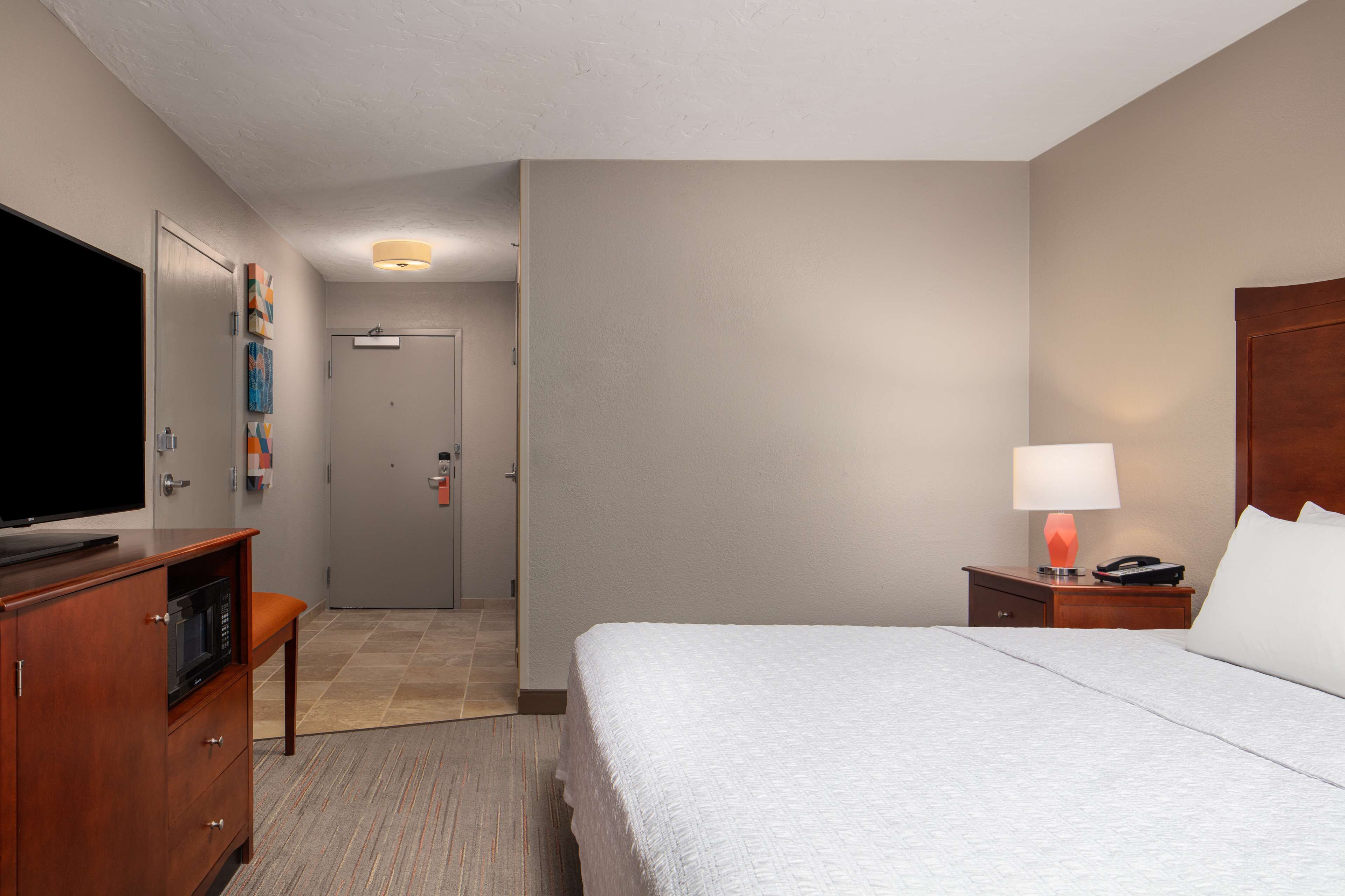 Une chambre d’hôtel avec un lit, une télévision, un bureau et une lampe.